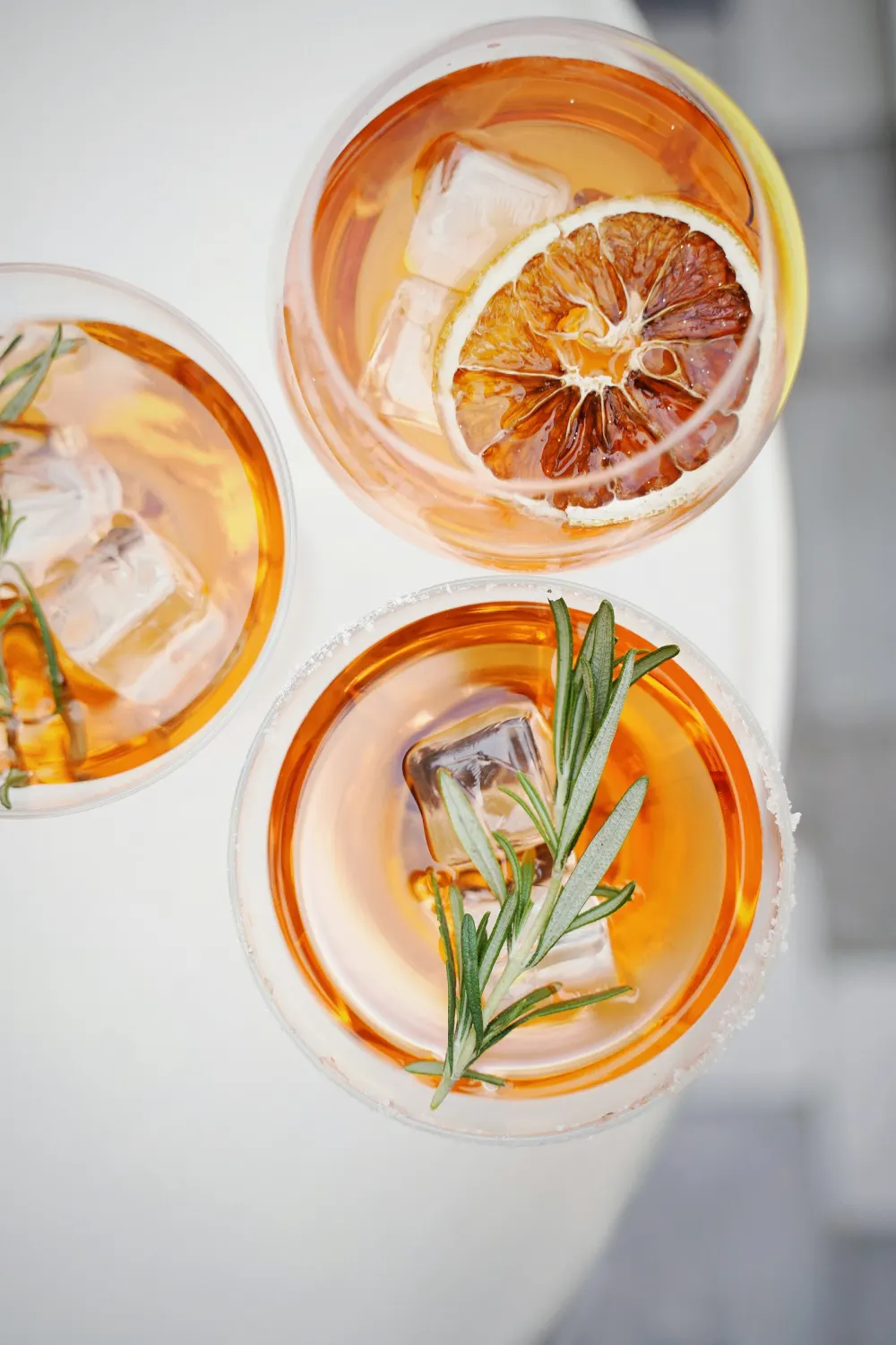 Two orange spritz cocktails with ice, dried orange and rosemary, seen from above